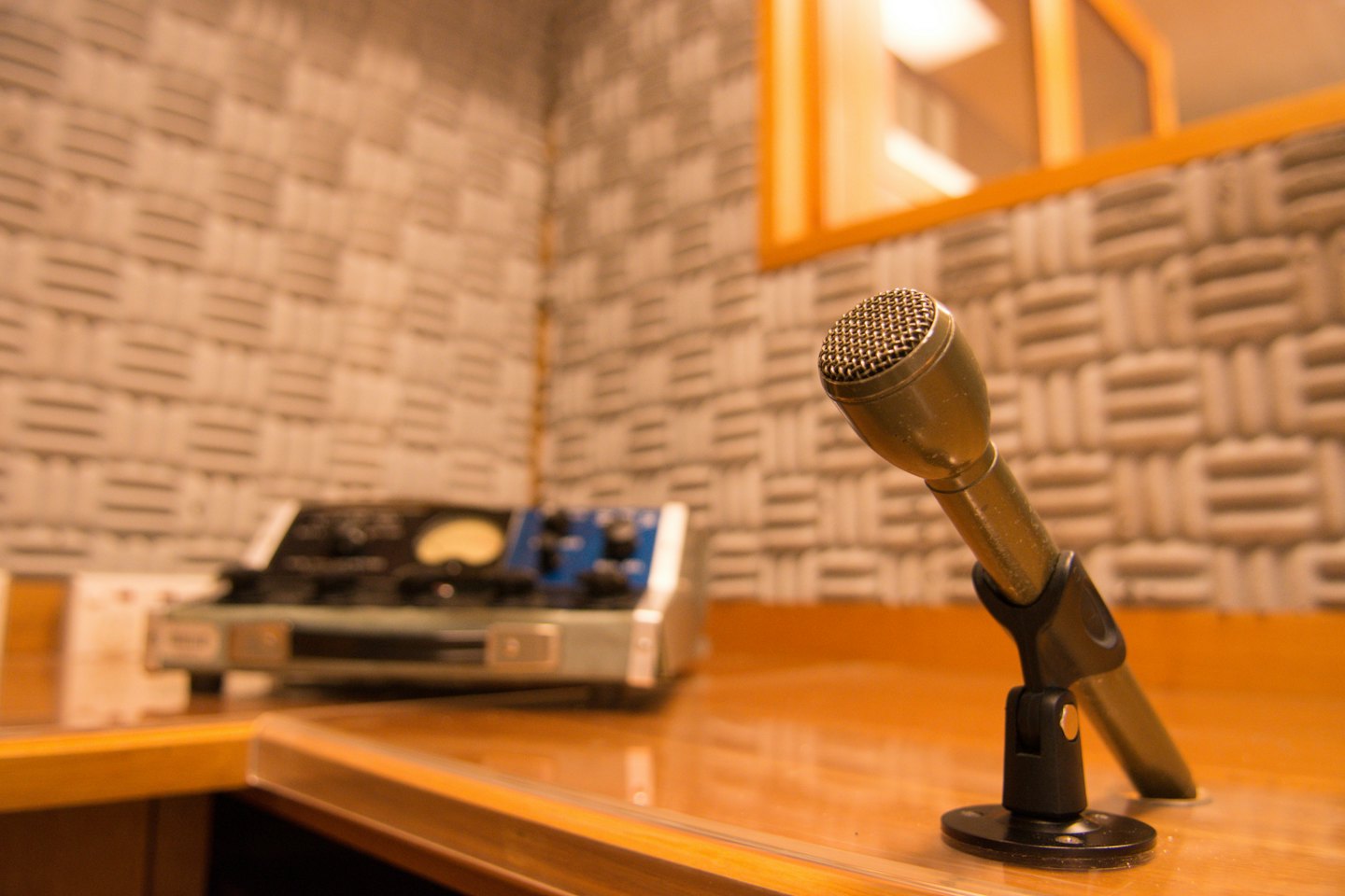 Classic microphone sits on a polished wooden desk in a studio.